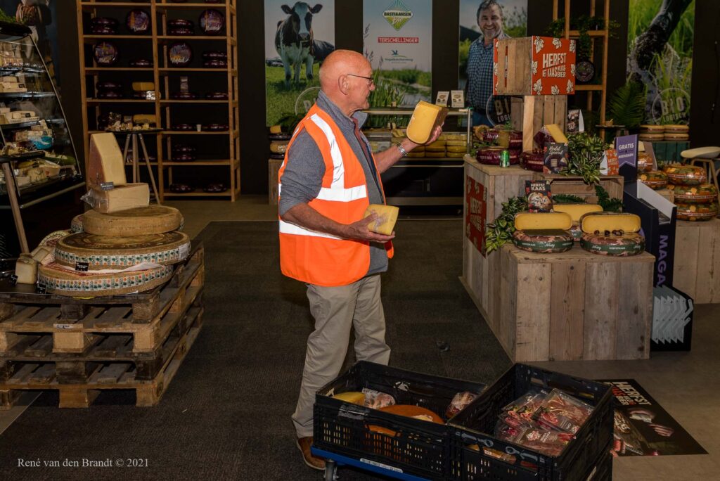 Vrijwilliger voedselbank vult kratten met kaas bij standhouder