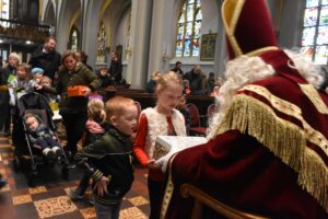 Kinderen brengen in de kerk hun schoenendoos met cadeautjes bij Sinterklaas